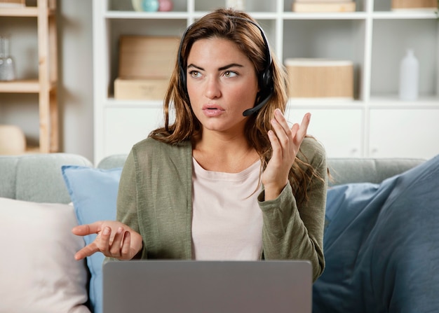 Donna con auricolare che ha videochiamata sul computer portatile