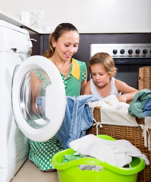 Donna con bambino vicino alla lavatrice