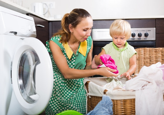 Donna con bambino vicino alla lavatrice