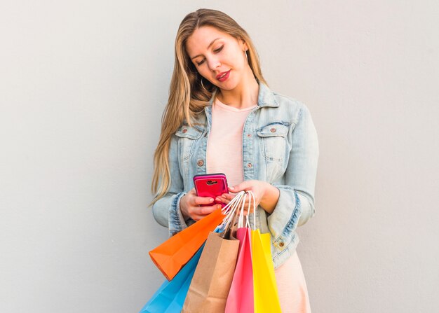 Donna con borse della spesa tramite smartphone