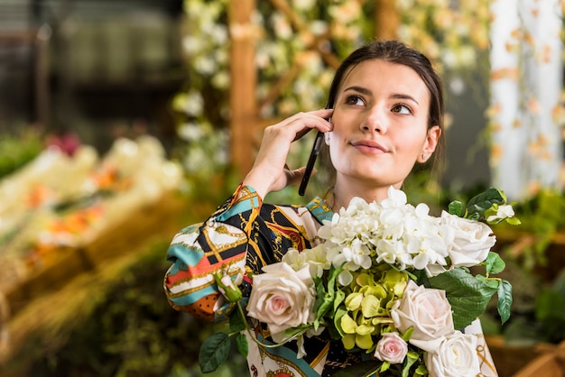 Donna con bouquet di fiori parlando per telefono