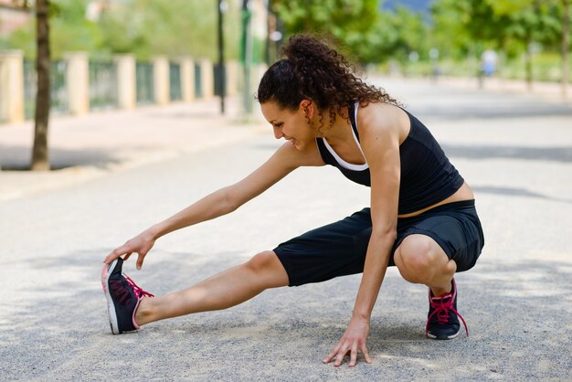 Donna con capelli ricci facendo stretching all&#39;aperto