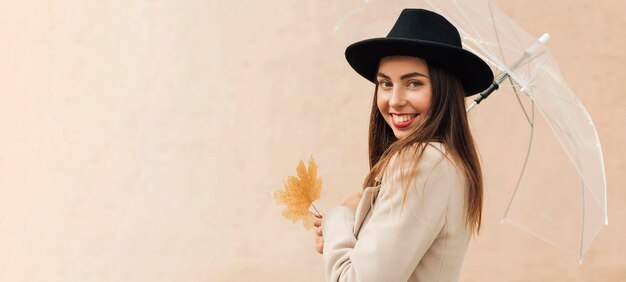 Donna con cappello nero che tiene un ombrello con lo spazio della copia