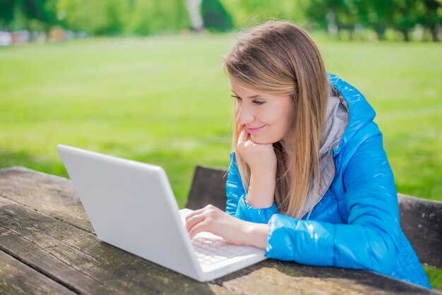 Donna con computer portatile nel giardino. Concetto di tempo libero. Istruzione di apprendimento o freelance di lavoro all&#39;aperto o concetto di concetto di rilassamento sfondo.