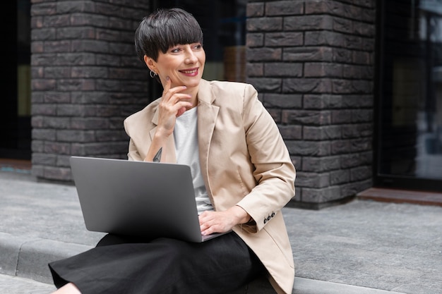 Donna con i capelli corti che controlla il suo laptop