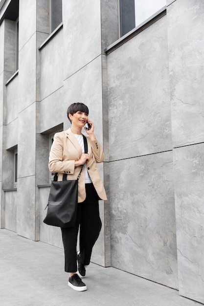 Donna con i capelli corti che parla al telefono all'aperto