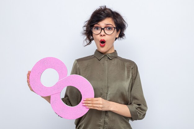 Donna con i capelli corti che tiene il numero otto di cartone che sembra sorpresa, giornata internazionale della donna, 8 marzo