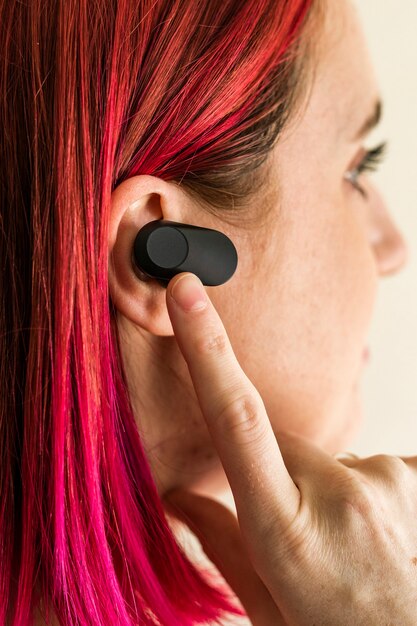 Donna con i capelli rosa che indossa auricolari wireless