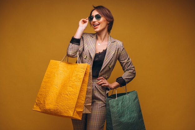 Donna con i sacchetti della spesa in studio su fondo giallo isolato