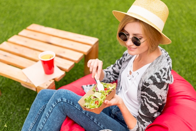 Donna con il cappello che mangia nel parco