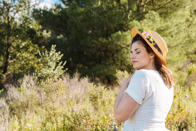 Donna con il cappello che posa con la vegetazione all'aperto