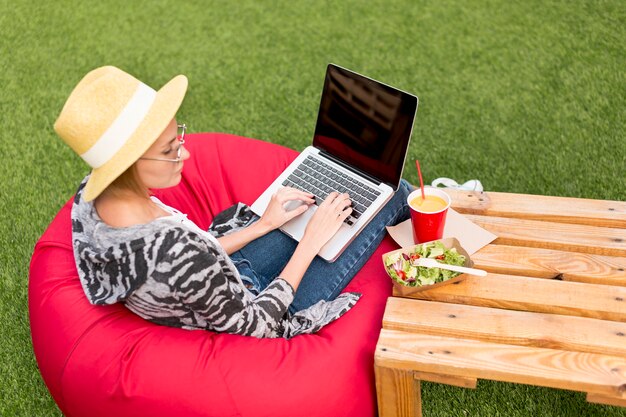 Donna con il computer portatile che esamina insalata