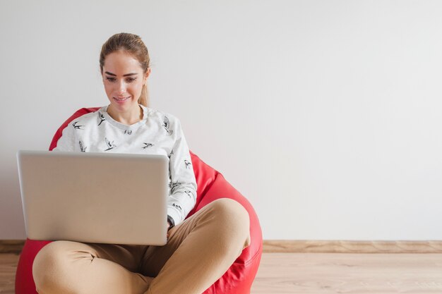 Donna con il computer portatile sulla poltrona