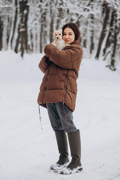 Donna con il suo cagnolino carino in un parco invernale