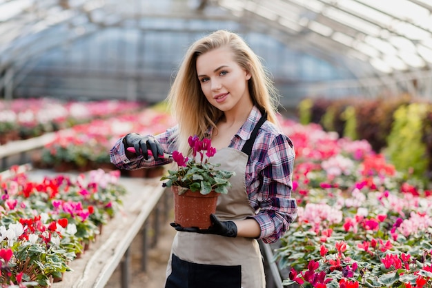 Donna con il vaso di fiori della tenuta del grembiule