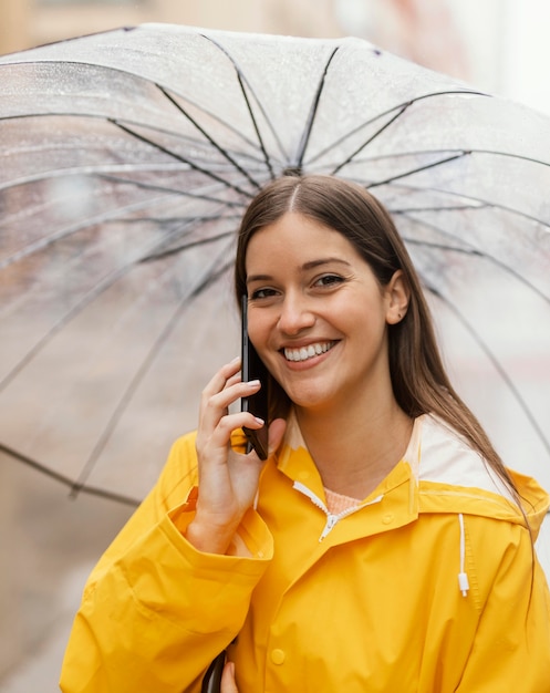 Donna con l'ombrello utilizzando il telefono cellulare