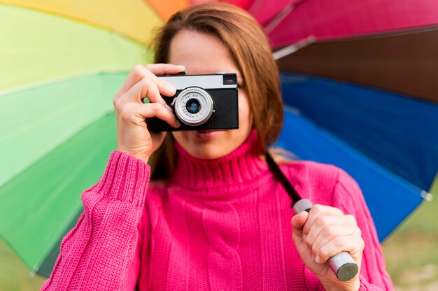 Donna con l'ombrello variopinto che prende una foto con la sua macchina fotografica