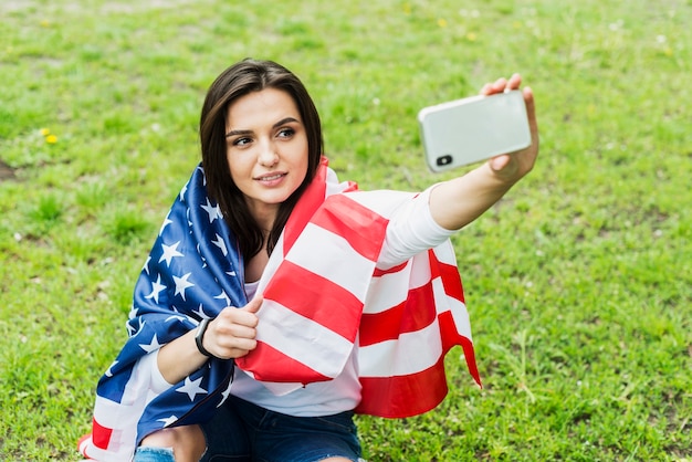 Donna con la bandiera americana prendendo selfie