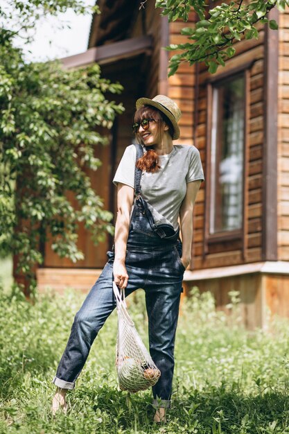 Donna con la borsa di eco con frutta in una campagna