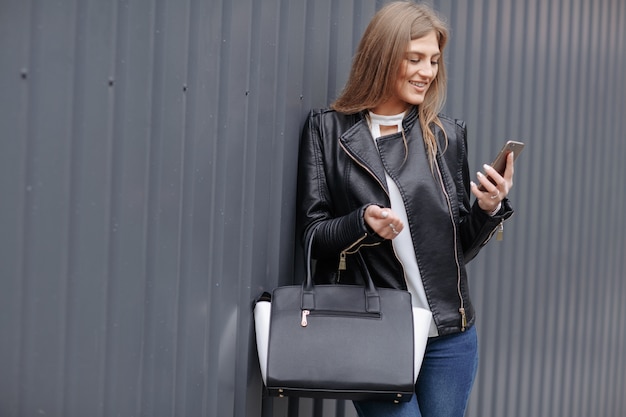 Donna con la borsa guardando il suo telefono cellulare