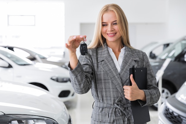 Donna con la chiave nera dell'automobile della tenuta della lavagna per appunti