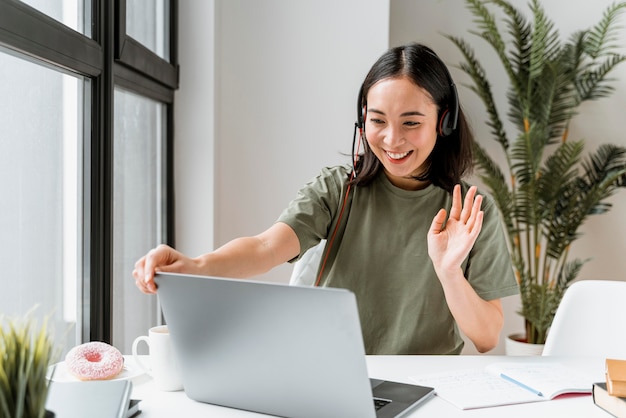 Donna con la cuffia avricolare che ha videochiamata sul computer portatile