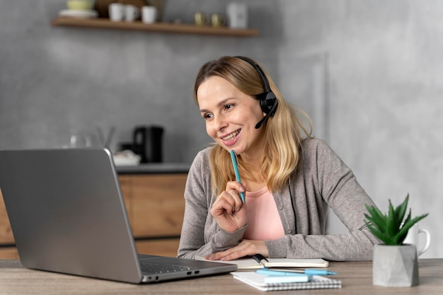 Donna con la cuffia avricolare che lavora al computer portatile