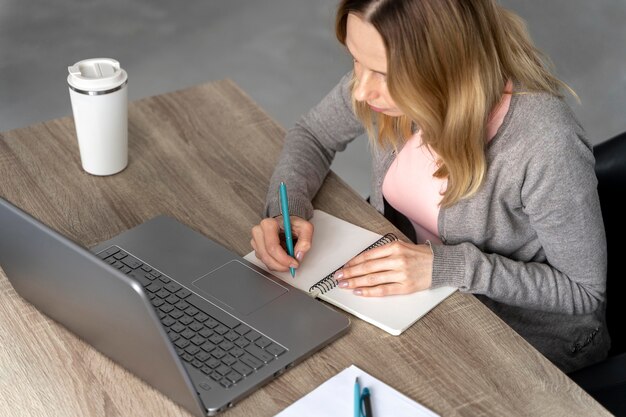 Donna con la cuffia avricolare che lavora al computer portatile