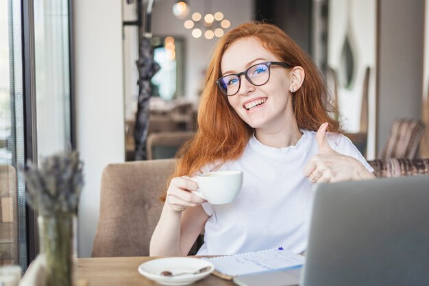 Donna con la tazza di caffè che mostra pollice in su