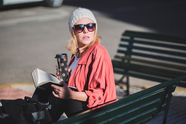 Donna con la tazza e libro che osserva via