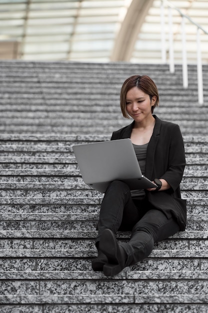 Donna con laptop seduta sulle scale