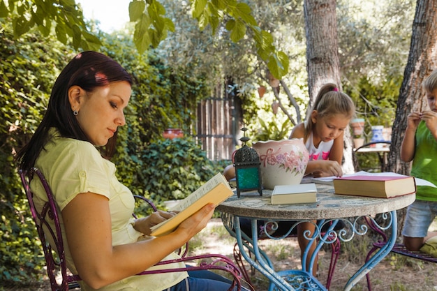 Donna con libro e bambini in giardino