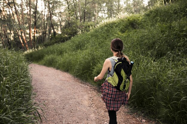 Donna con lo zaino che cammina nel sentiero forestale