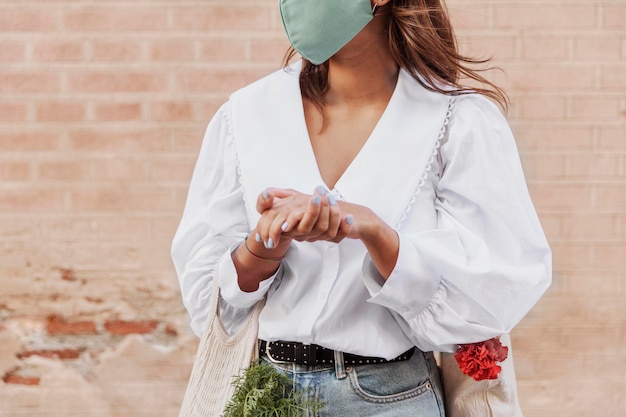 Donna con maschera facciale utilizzando disinfettante per le mani