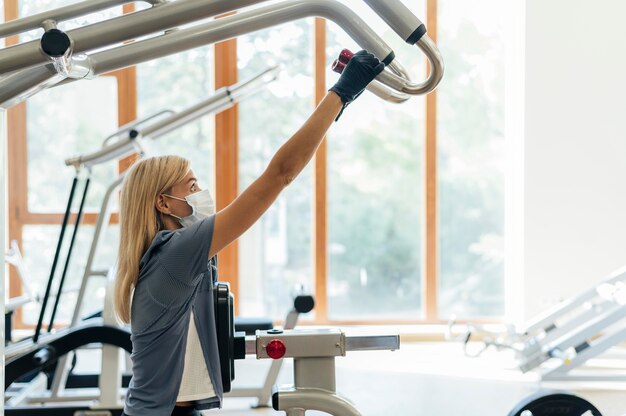 Donna con maschera in palestra utilizzando attrezzature