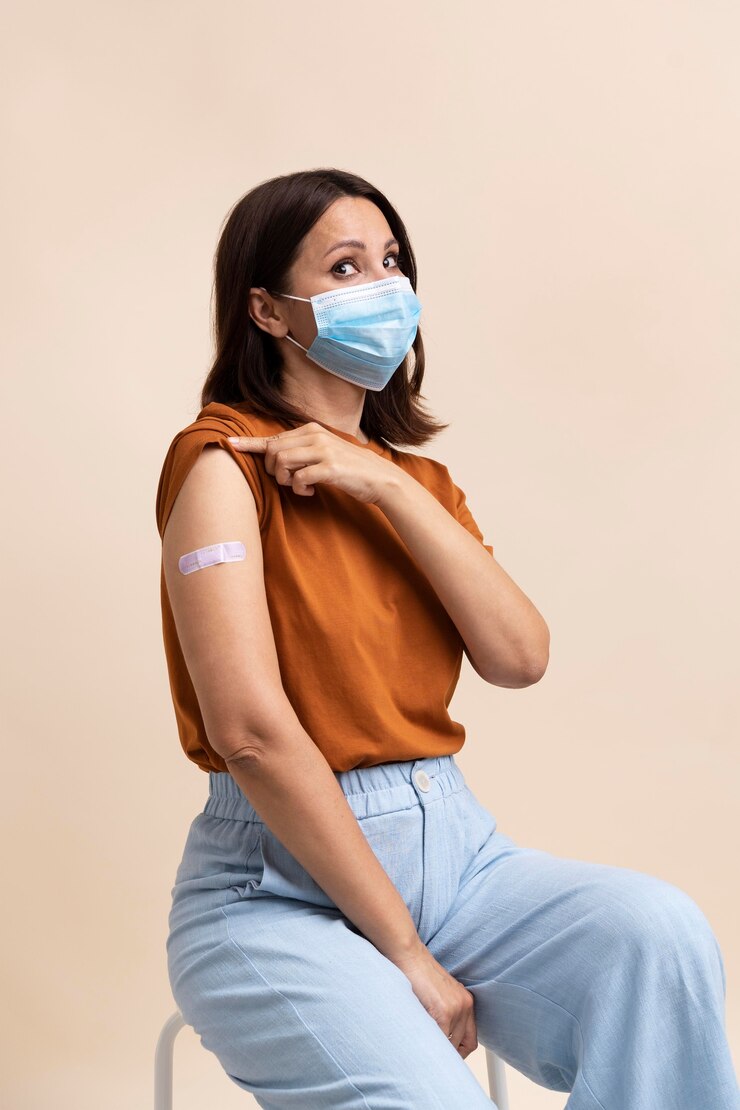 Foto gratuito donna con maschera medica che mostra adesivo sul braccio dopo aver ricevuto un vaccino