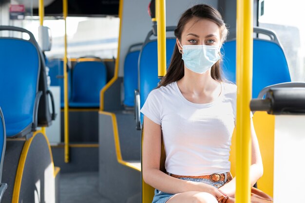 Donna con maschera medica che utilizza autobus pubblico per il trasporto