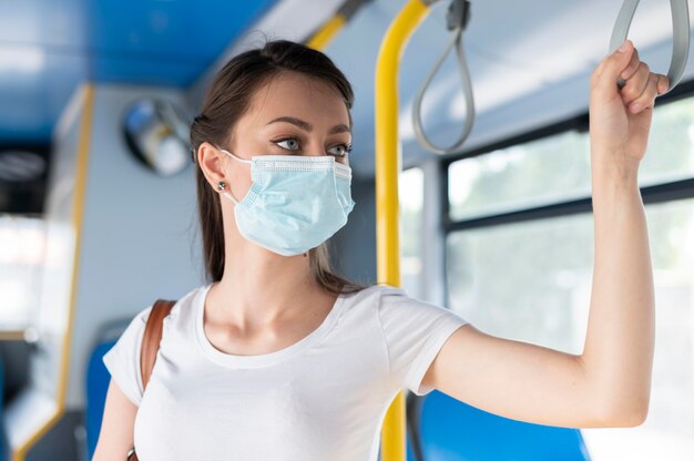 Donna con maschera medica che utilizza autobus pubblico per il trasporto