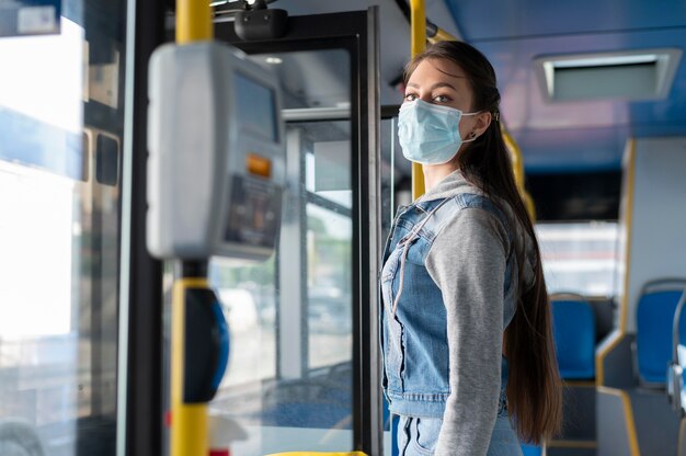 Donna con maschera medica che utilizza autobus pubblico per il trasporto