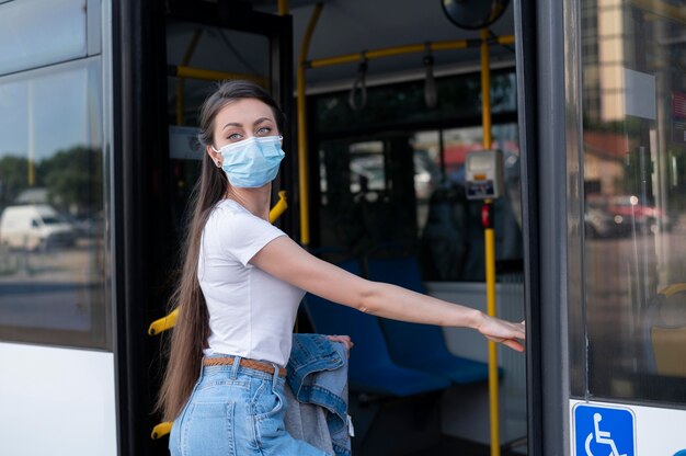 Donna con maschera medica che utilizza autobus pubblico per il trasporto