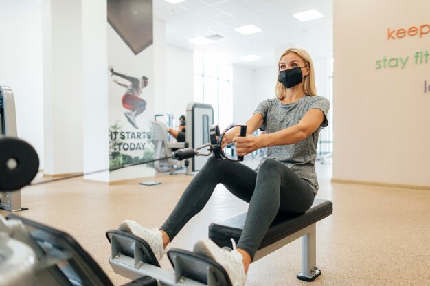 Donna con mascherina medica che lavora in palestra durante la pandemia