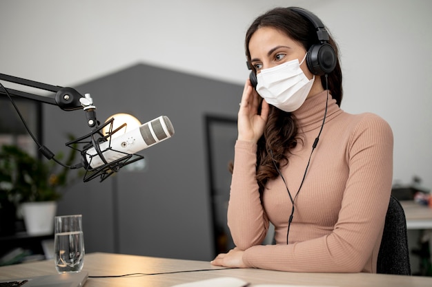 Donna con mascherina medica che trasmette alla radio