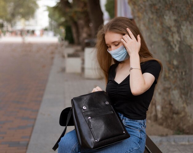Donna con mascherina medica seduta su una panchina all'esterno