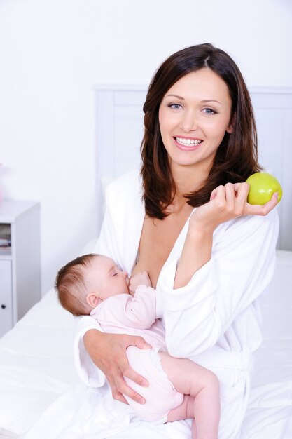 Donna con mela verde che allatta al seno il suo bambino