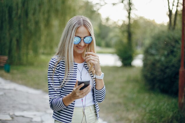 donna con occhiali da sole a digitare sorridente su un cellulare