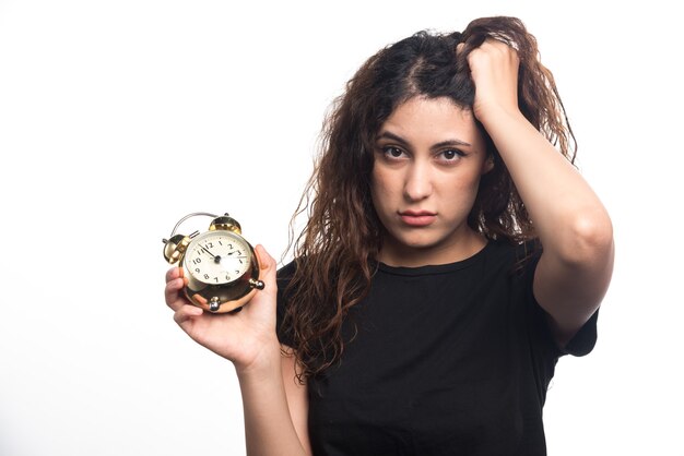 Donna con orologio che tiene la sua testa su sfondo bianco. Foto di alta qualità