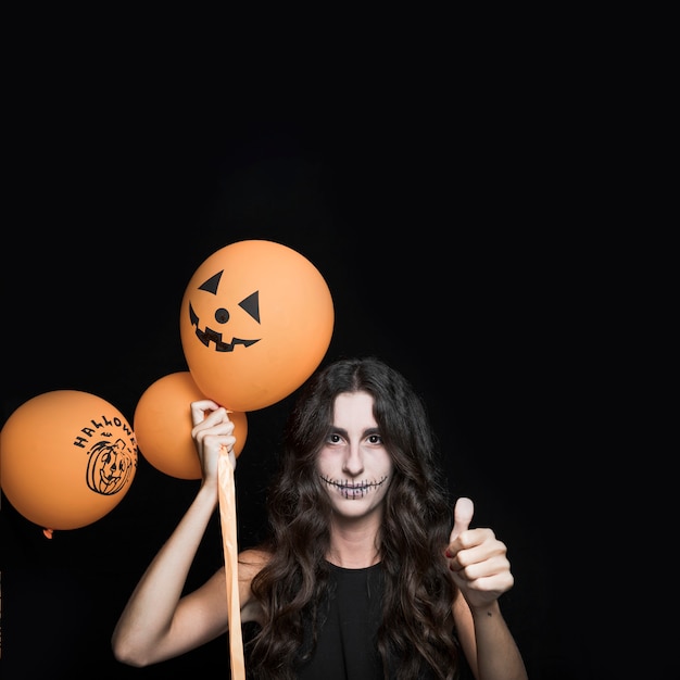 Donna con palloncini di Halloween mostrando buon segno