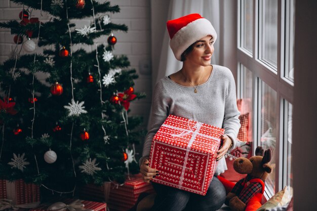 Donna con regali di Natale dall&#39;albero di Natale