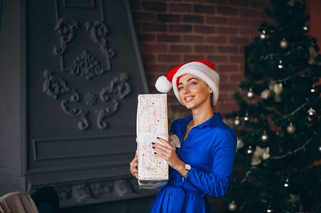 Donna con regali e in piedi davanti all&#39;albero di Natale