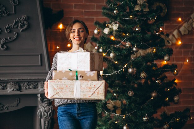 Donna con regali in piedi davanti all&#39;albero di Natale